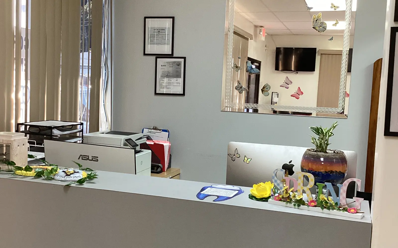 The front desk at Diamond's Dental Inc., with a computer, seasonal decorations, and framed City of La Habra licenses on the wall